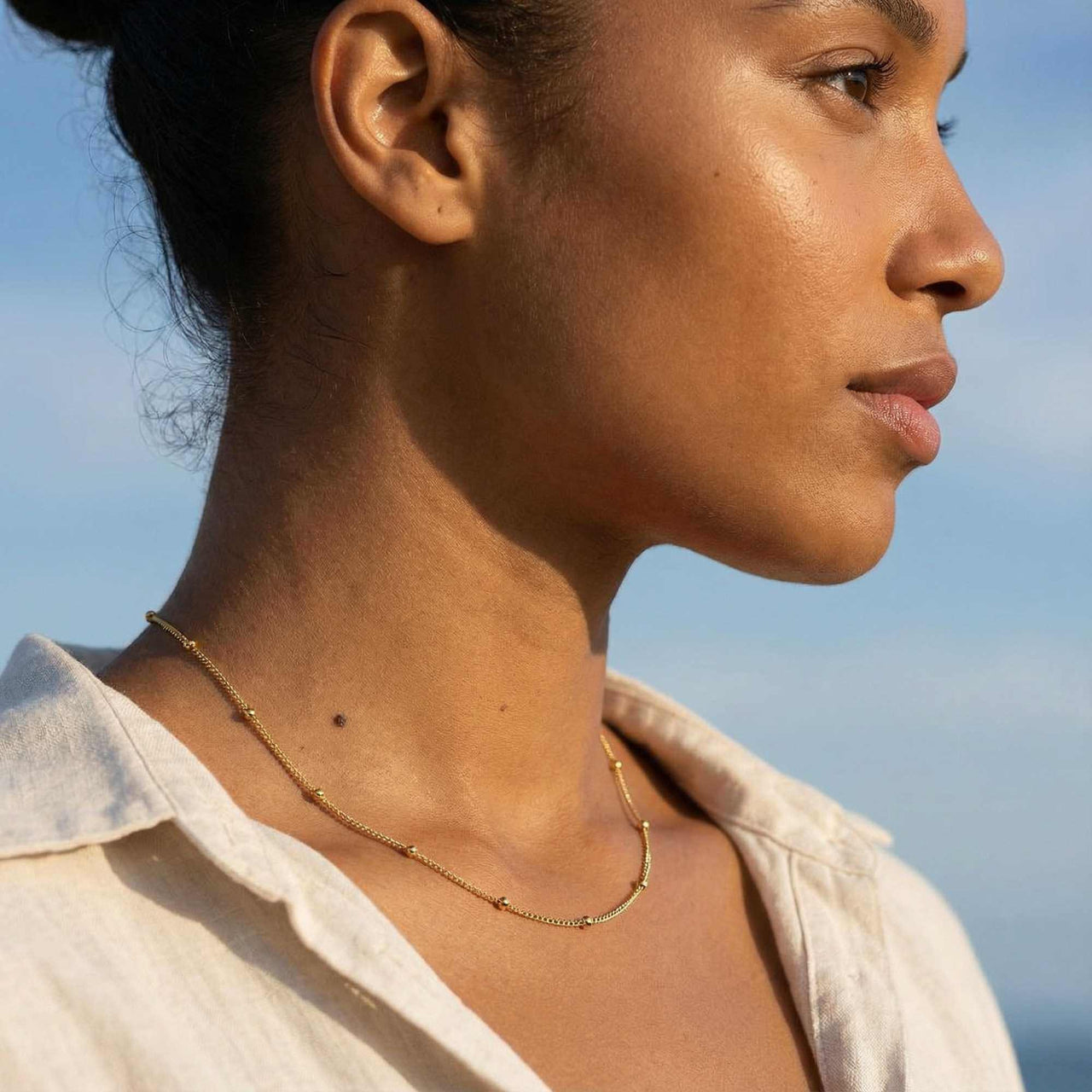 Julia Beaded Chain Necklace worn by a woman, featuring a whisper-thin chain with golden beads by Brother & Sisters.