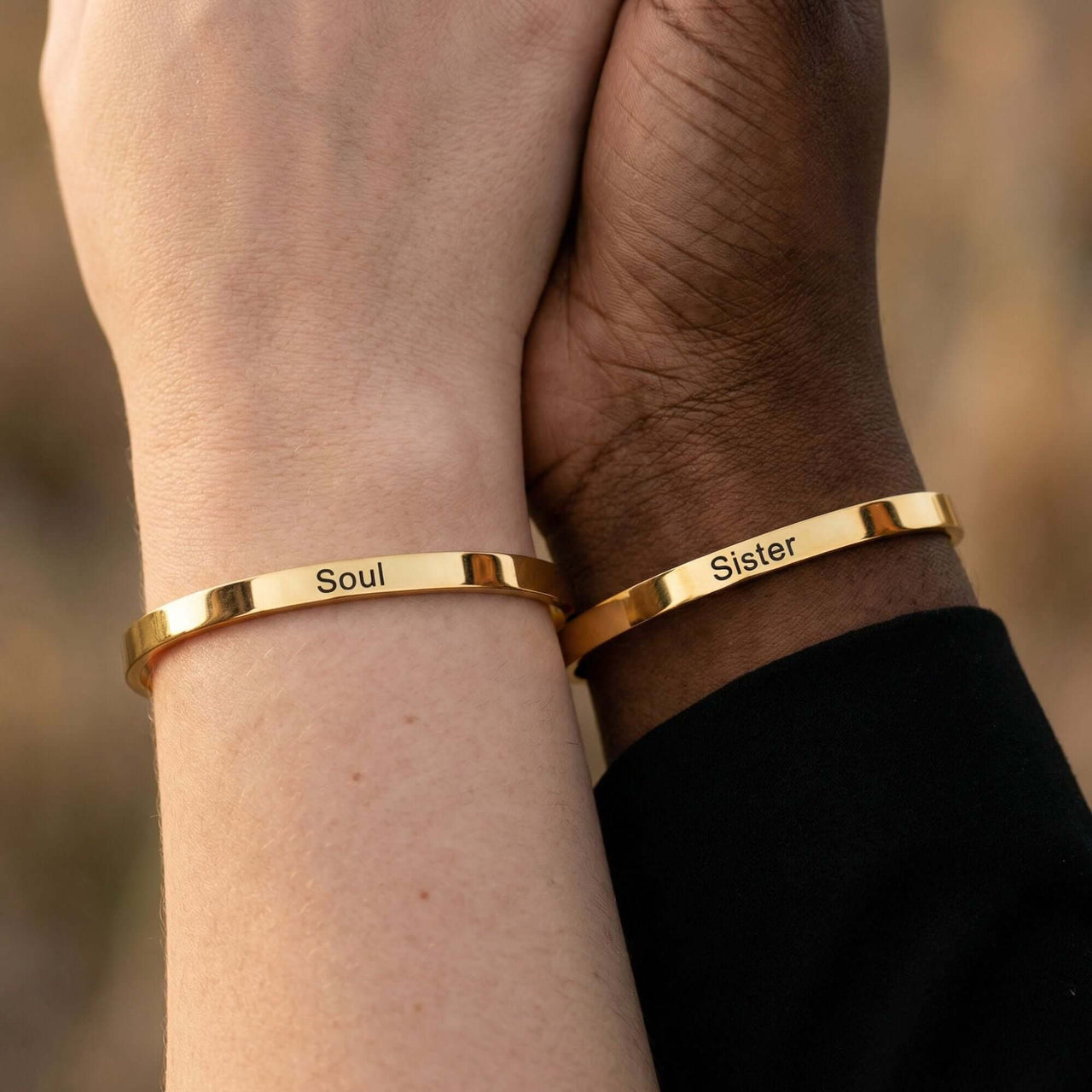 Matching Couple Bracelet showing gold cuffs engraved with 'Soul' and 'Sister', designed by Brother & Sisters.