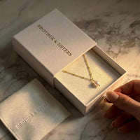 Thumbnail for Pearl Drop Necklace in packaging from Brother & Sisters, featuring a lustrous baroque pearl and textured satellite chain.