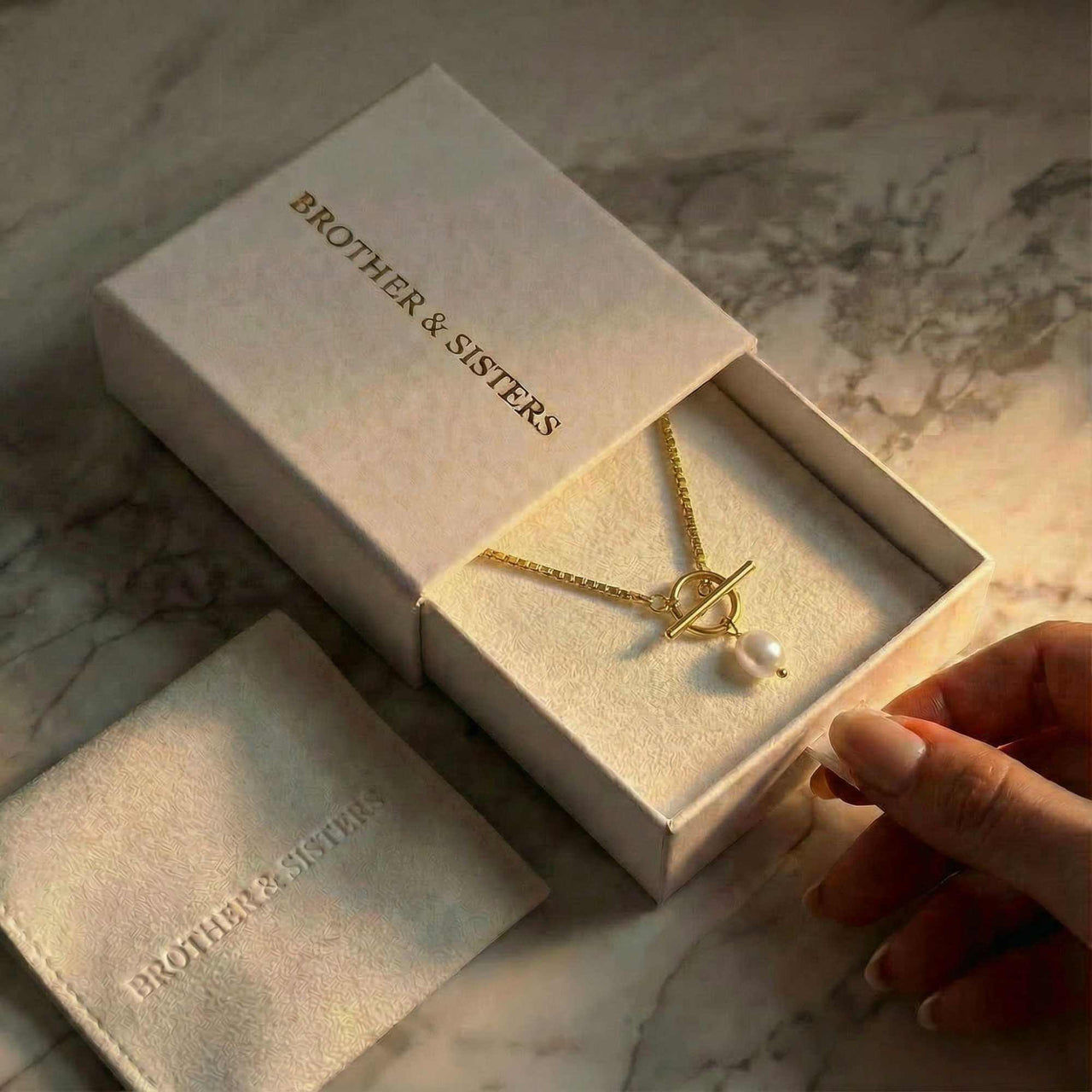 La Isla Pearl Toggle Necklace in a Brother & Sisters box with a gold toggle and freshwater pearl.