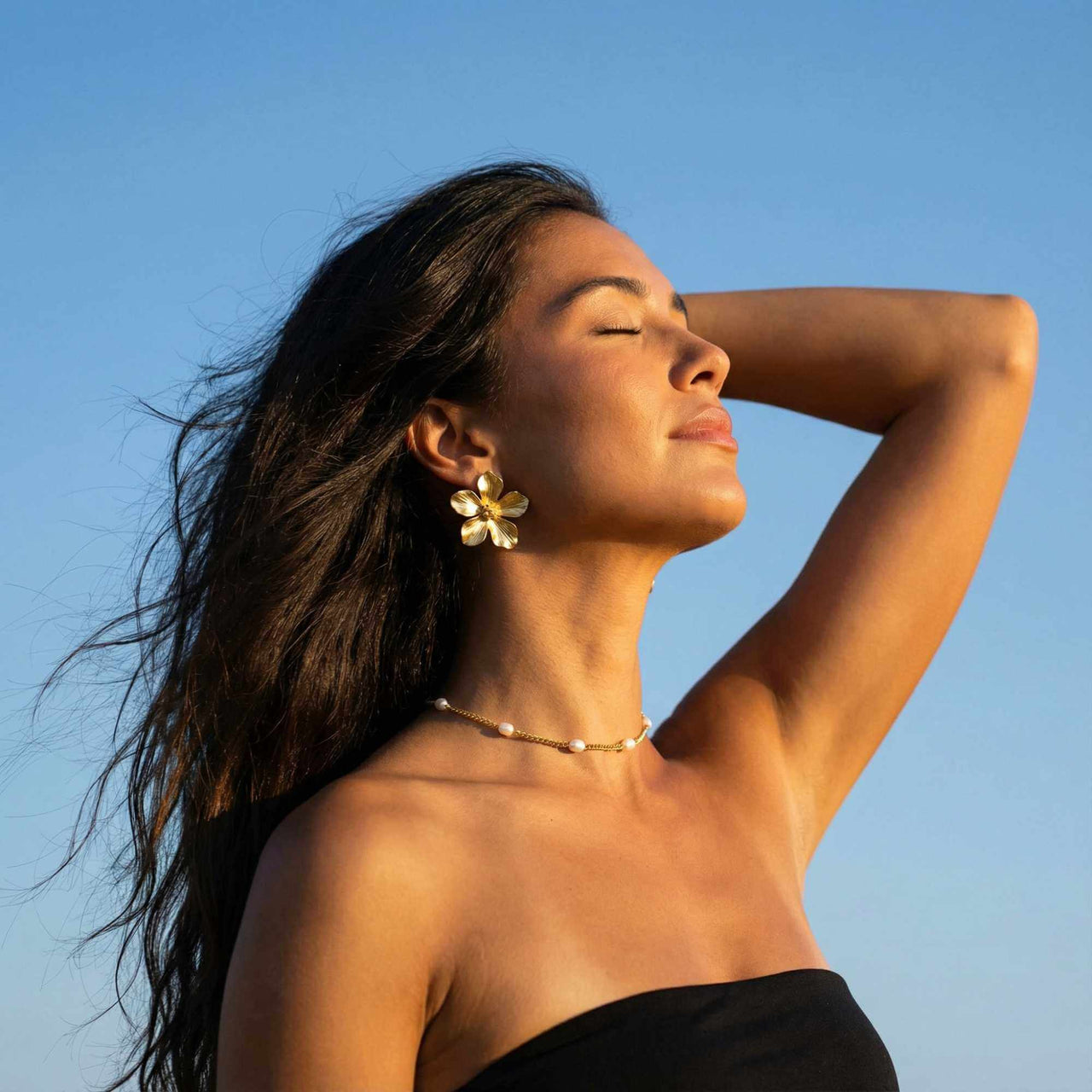 Dainty Pearl Choker worn with floral earrings by Brother & Sisters, showcasing elegance against a clear blue sky.