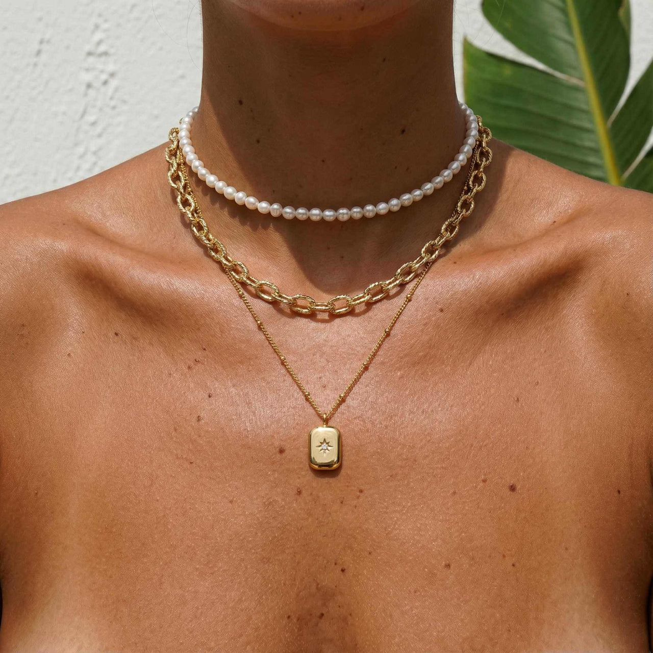 Starlight Pendant Necklace by Brother & Sisters close-up on model, featuring gold tag pendant with starburst detail.