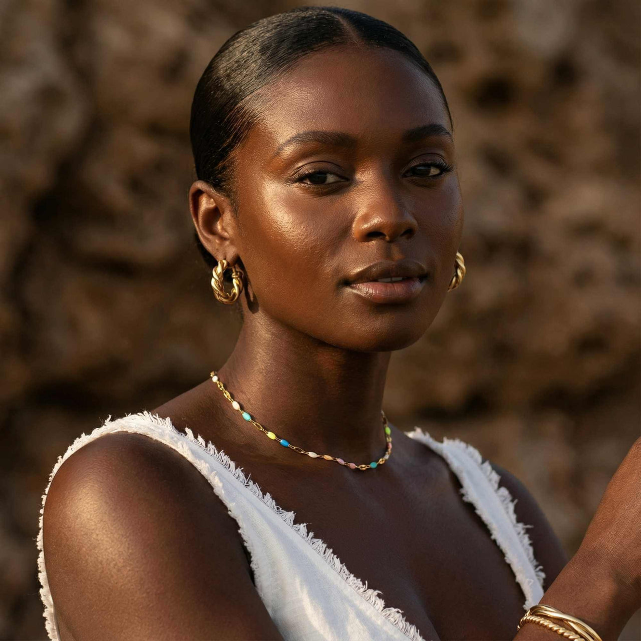 A model wearing the Rainbow Choker by Brother & Sisters, featuring colorful enamel beads and a gold chain.