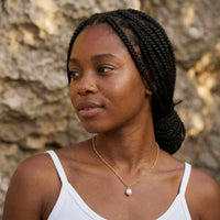 Thumbnail for Pearl Drop Necklace worn by a woman with braided hair, showcasing its elegant design and lustrous pearl.