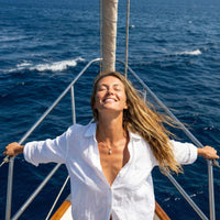 Thumbnail for Astra Teardrop Necklace worn by a woman on a boat, illuminated against the ocean backdrop, by Brother & Sisters.