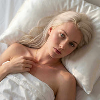 Thumbnail for Julia Beaded Chain Necklace worn by a model resting on a pillow, showcasing its delicate golden beads.