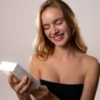 Thumbnail for Smiling woman holding a gift box, excited to unveil the Love Photo Necklace by Brother & Sisters.