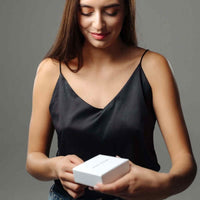 Thumbnail for Woman unboxing a Sunflower Photo Necklace gift box by Brother & Sisters, wearing a stylish black top.