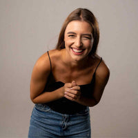 Thumbnail for Smiling young woman wearing a black top and blue jeans, exuding joy and happiness.