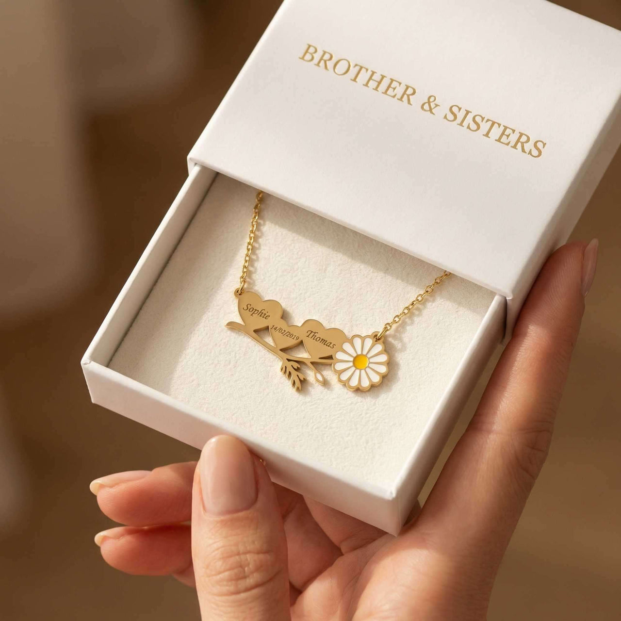 Daisy Name Necklace by Brother & Sisters displayed in a gift box, featuring engraved hearts and a delicate enamel daisy.
