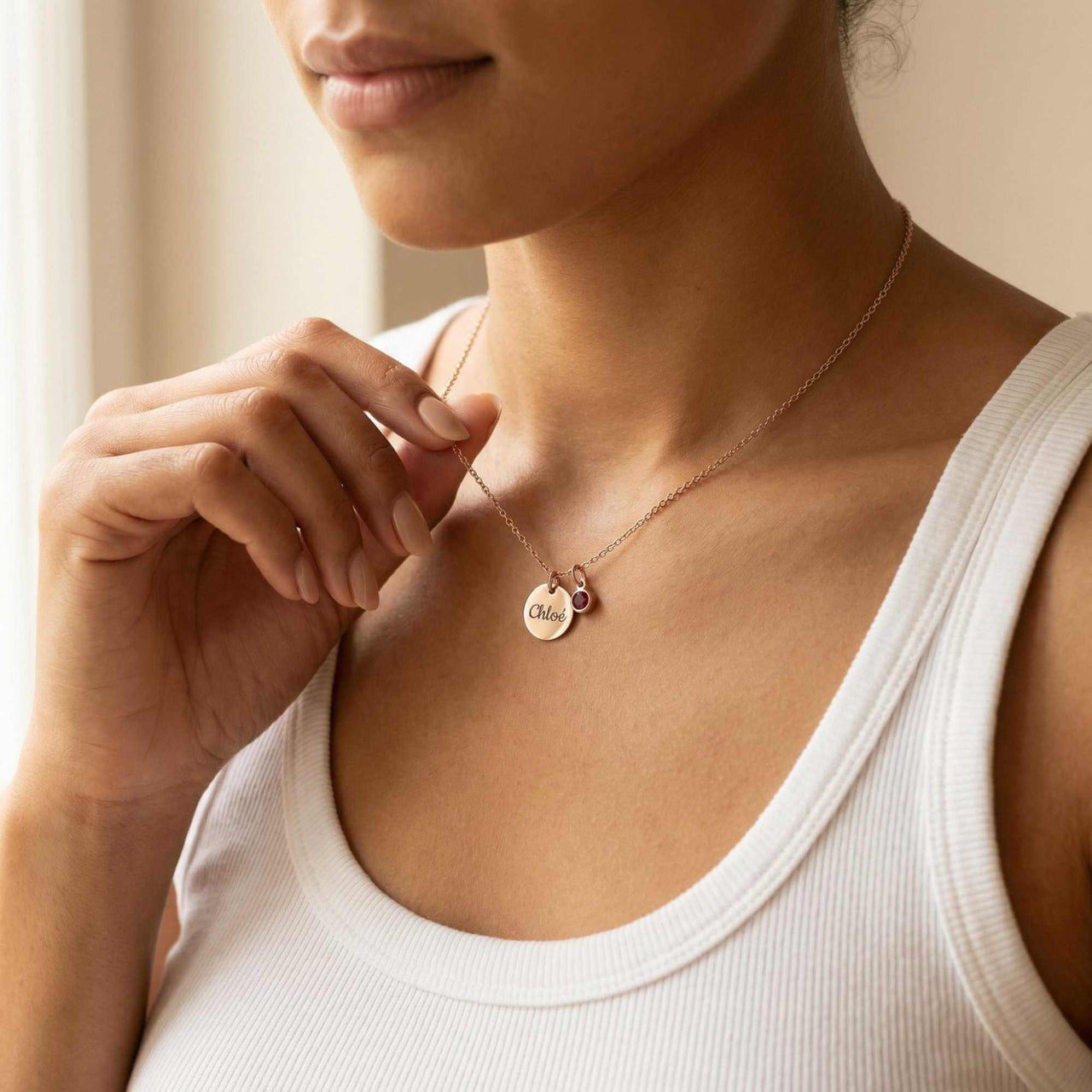 Close-up of a woman wearing a Precious Name Necklace with the name 'Chloe' and a birthstone crystal by Brother & Sisters.