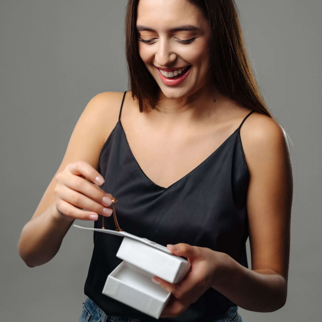 A woman joyfully unboxing the Classic Name Necklace from Brother & Sisters, showcasing its personalized design.