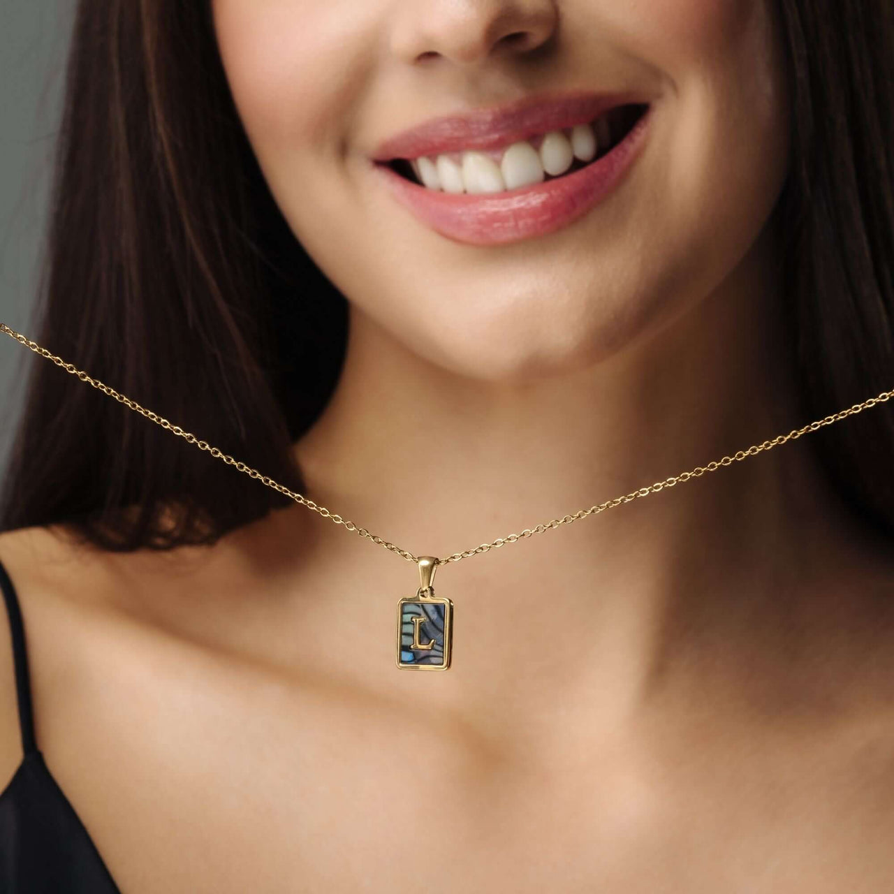 Happiness Initial Necklace displayed on a smiling woman, showcasing its elegant gold design by Brother & Sisters.