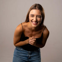 Thumbnail for Smiling woman wearing a black top and denim skirt, showcasing happiness and joy.