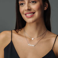 Thumbnail for Heart Name Necklace worn by a smiling woman, featuring a custom nameplate and heart charm, by Brother & Sisters.