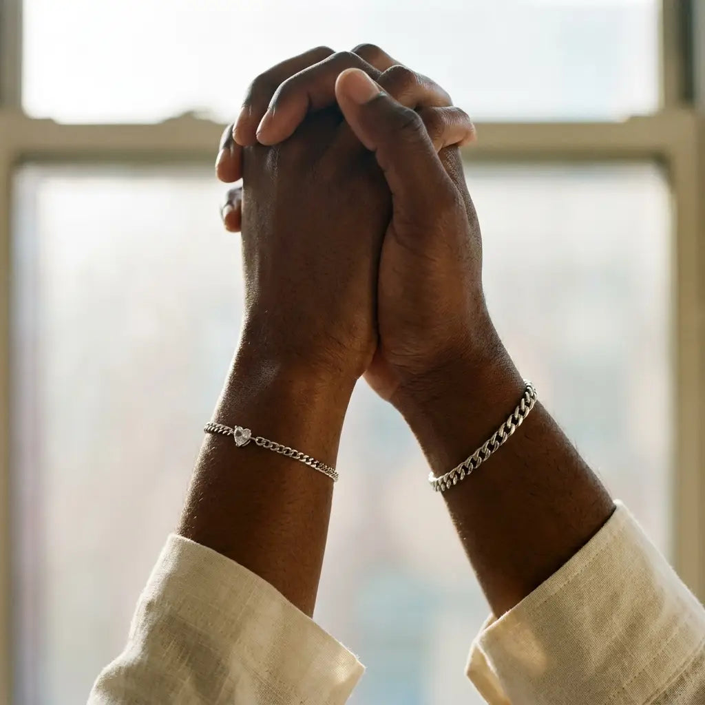 Black couple raised hands joined wearing matching silver Heart Bond bracelets