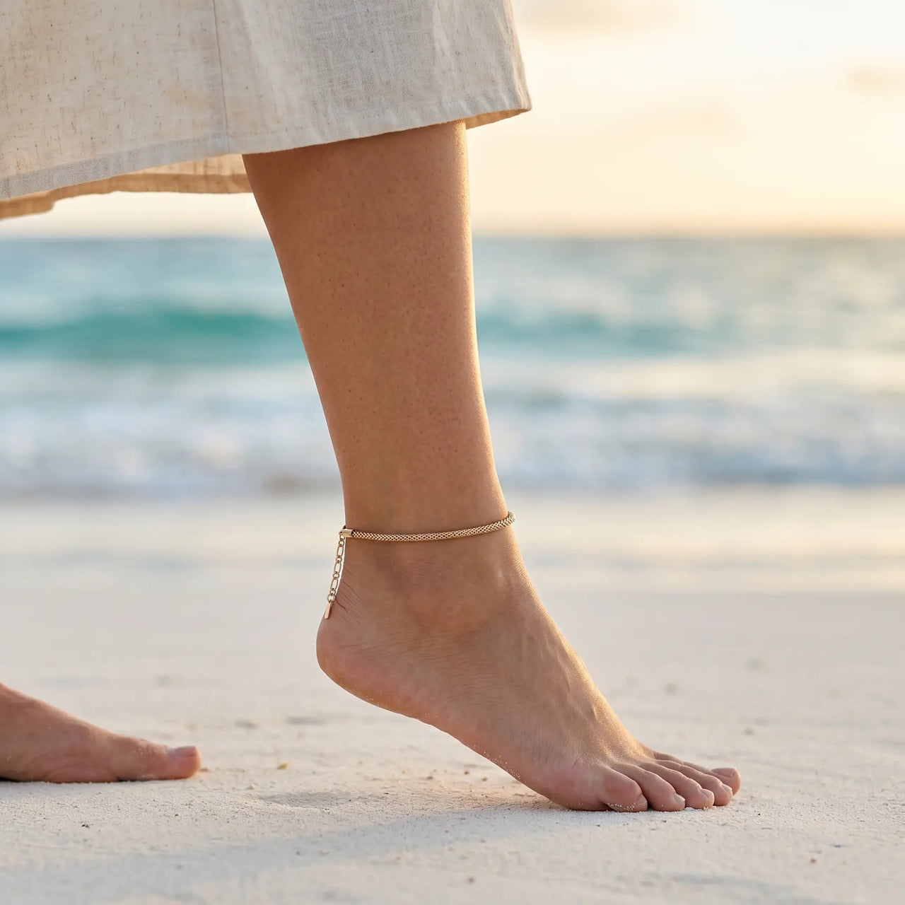 Maëlle delicate gold tube-mesh anklet on Mexican Latina ankle walking on Tulum white powder sand beach at golden hour sunset — refined bohemian summer