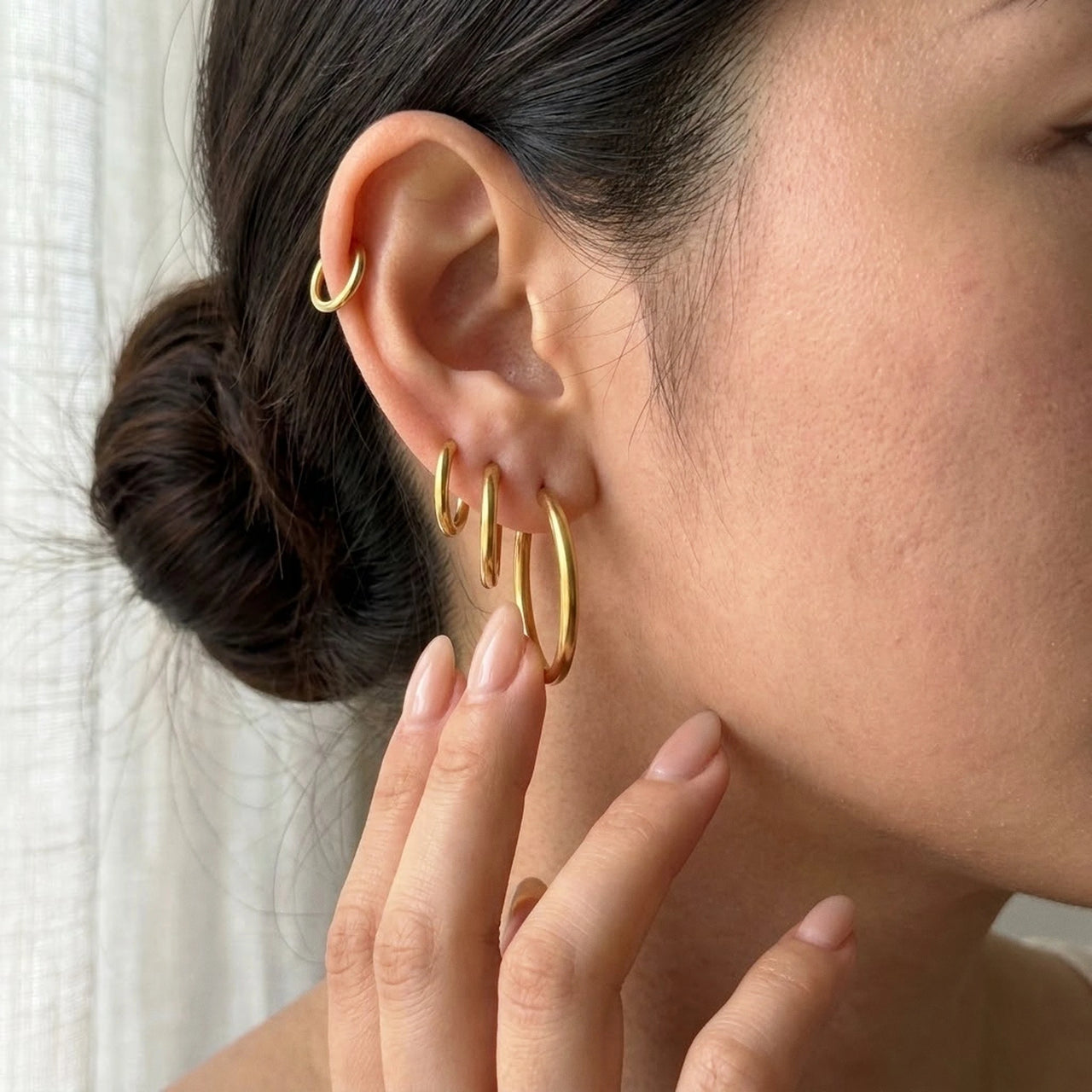 Huggie Hoop Earrings Set of 4 Pairs in Gold held between the fingertips, scale reference | SKU: huggie-set-gold