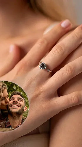 Close-up view of a woman showcasing a sterling silver adjustable projection ring, featuring a subtle floral design and a dark, central memory stone. An embedded image highlights the personalized aspect, showing a joyful couple embracing.
