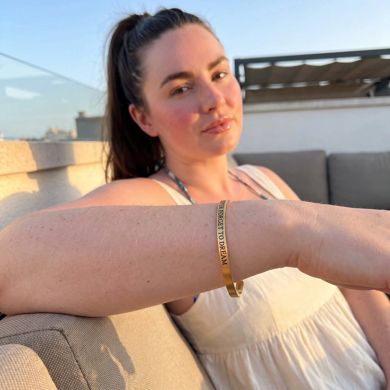Never Forget To Dream bracelet in gold worn during a relaxed moment | SKU: nftd-g