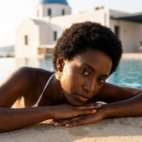 Thumbnail for Pave Cross Huggie Hoops in Gold, worn by a pool in Santorini | SKU: 41006-gold
