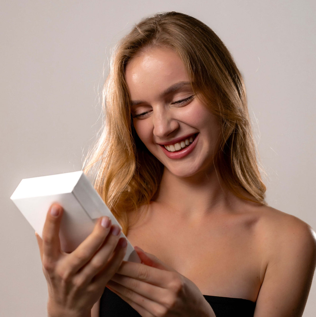 Smiling woman opening a gift box, excited about the Timeless Photo Necklace by Brother & Sisters.