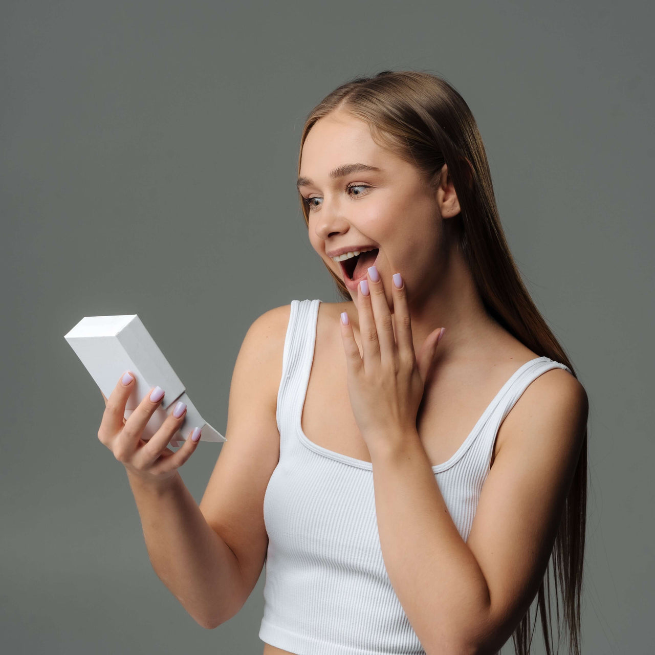 Young woman excitedly opening a gift box, showcasing surprise and joy.
